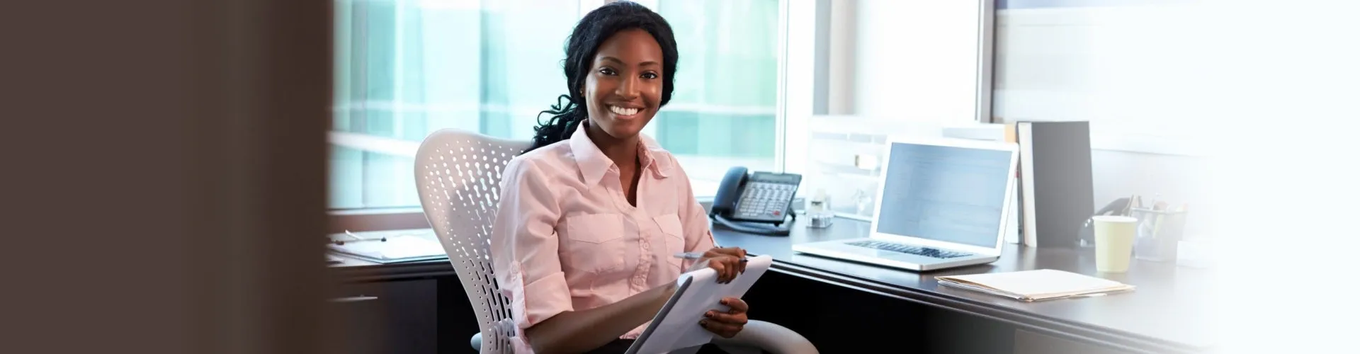 A woman sitting at her desk writing on paper.