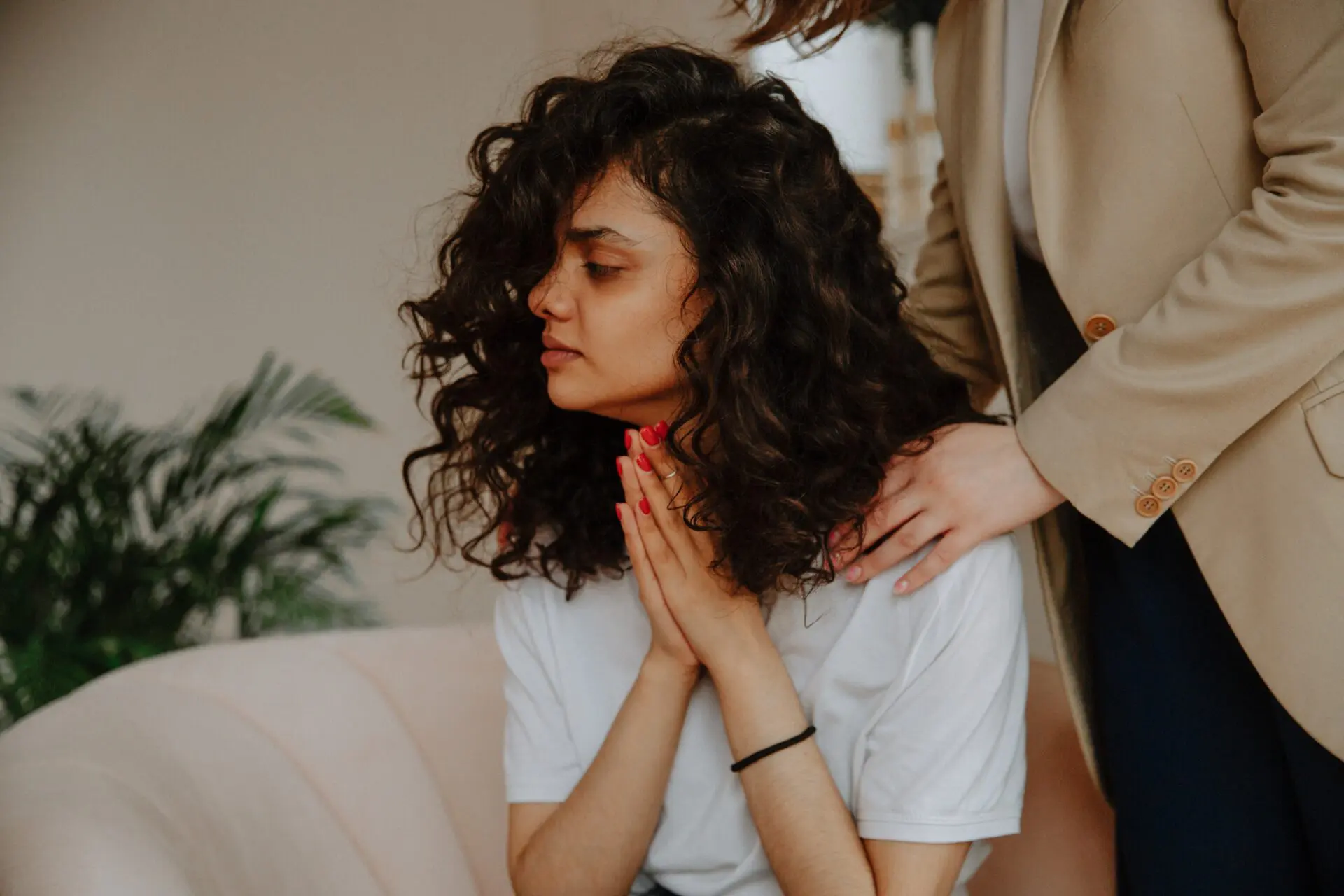 A woman with her hands clasped together in front of a man.